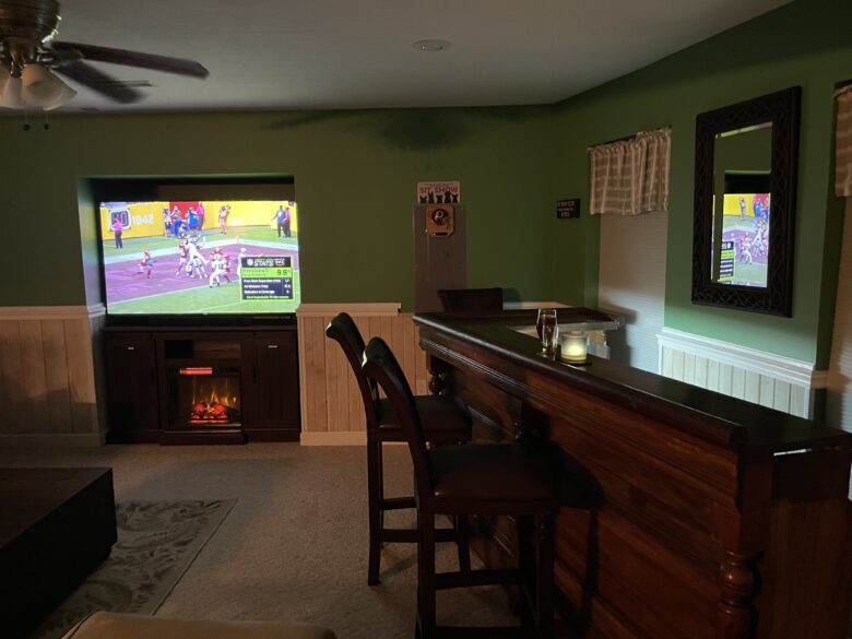 The antique bar with the big TV and the fireplace lit behind it
