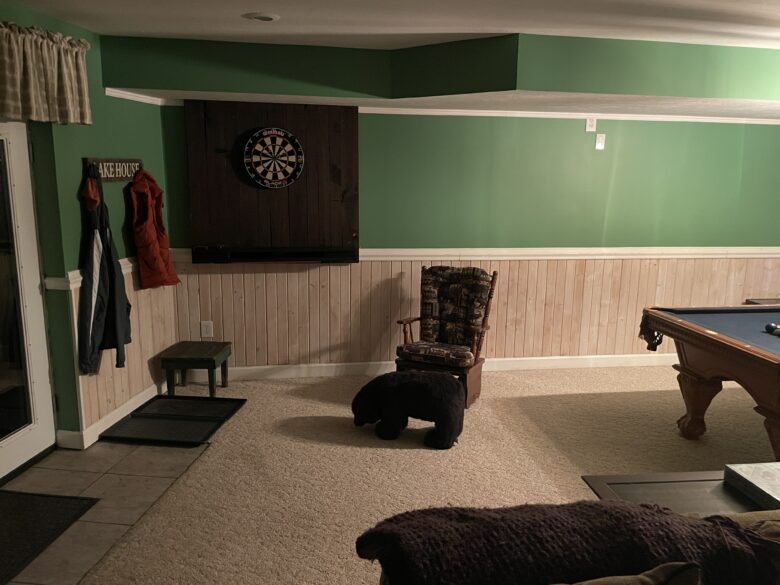 The dartboard on the game room wall, pool table to the right