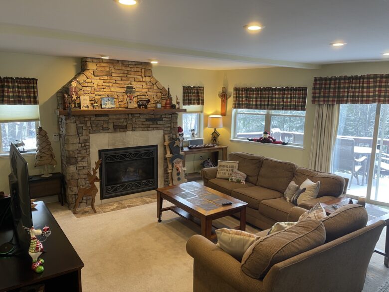 The main-floor living room in daylight, stone fireplace and sofas