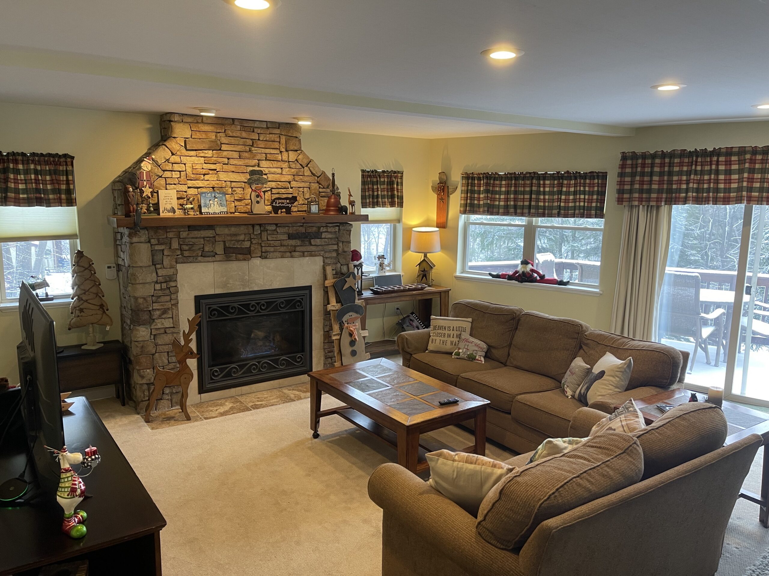 The main-floor living room in daylight, stone fireplace and sofas