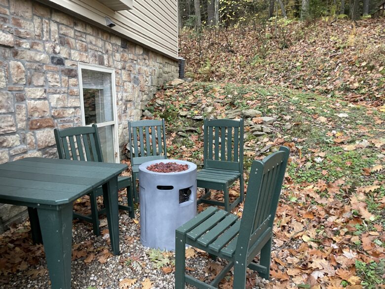 A portable fire bowl and chairs on the gravel beside the house in autumn - not the wood-burning fire pit at the rear